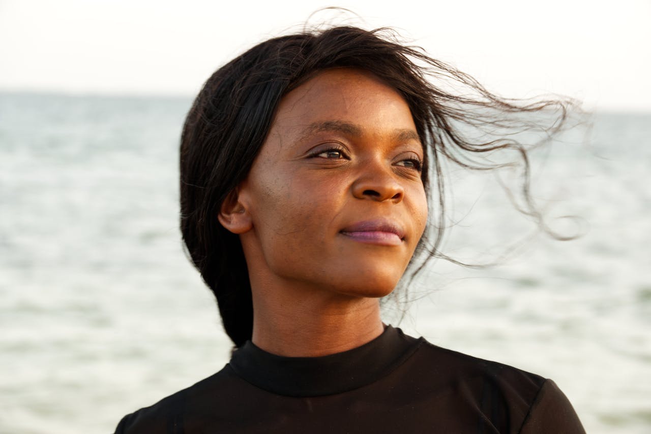 A thoughtful woman enjoys a breezy day by the sea in Mombasa, Kenya.