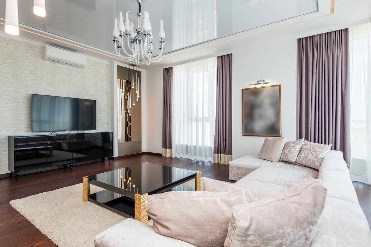 A sophisticated modern living room featuring a chandelier, plush furniture, and elegant decor.